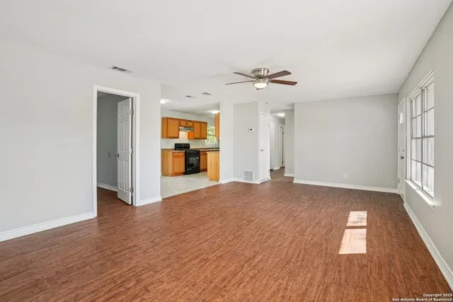 an empty room with wooden floor and windows