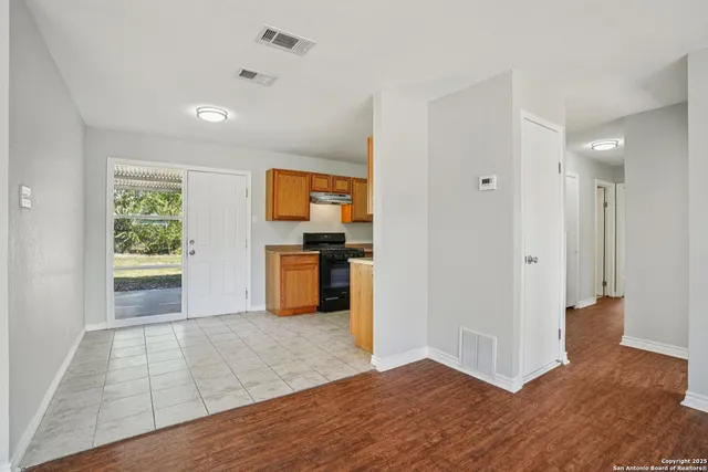 a view of empty room with kitchen and window