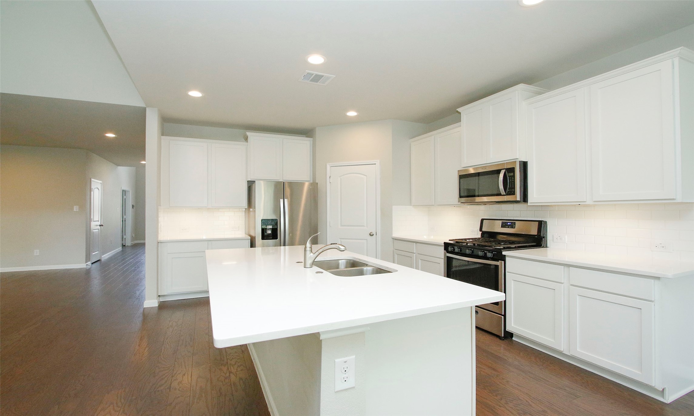 14120 Sand Ridge Court Conroe, TX 77384 - Photo 16 of 43 a kitchen with a sink a stove a refrigerator and white cabinets with wooden floor