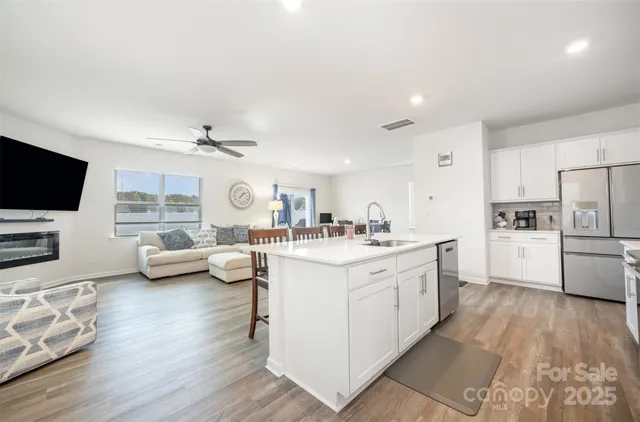 a large white kitchen with lots of counter top space a sink and stainless steel appliances