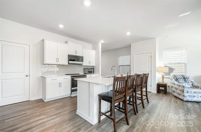 a large white kitchen with lots of counter top space and stainless steel appliances