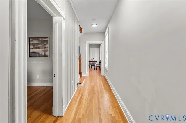 a view of a hallway with wooden floor and a bathroom