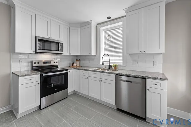 a kitchen with granite countertop white cabinets and stainless steel appliances