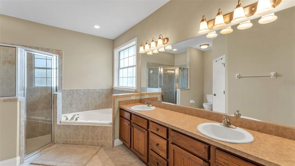 730 Country Walk Cove Eagle Lake, FL 33839 - Photo 18 of 38 a bathroom with a granite countertop sink a large mirror and a bathtub