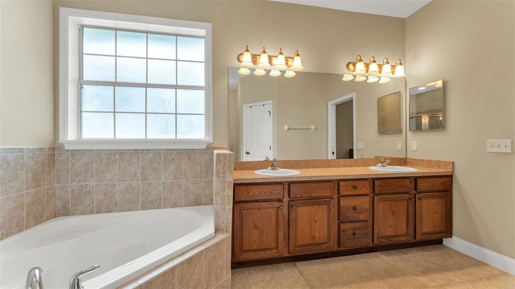 730 Country Walk Cove Eagle Lake, FL 33839 - Photo 20 of 38 a bathroom with a tub a double vanity sink and a mirror