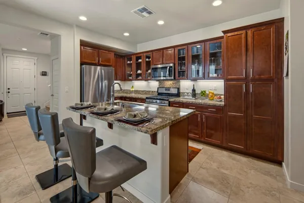 a kitchen with granite countertop kitchen island stainless steel appliances a refrigerator a stove a sink and a center island