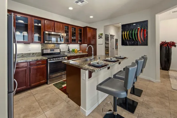 a kitchen with stainless steel appliances granite countertop a stove top oven a sink and a refrigerator