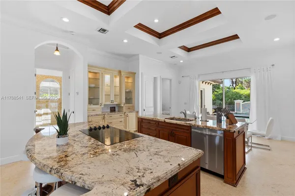 a kitchen with granite countertop kitchen island stainless steel appliances a sink and a refrigerator