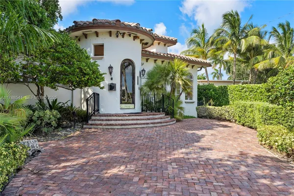 a view of a house with a yard and coconut trees