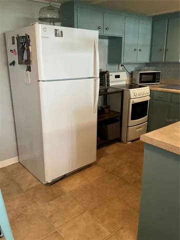 a white refrigerator freezer and a stove sitting inside of a kitchen