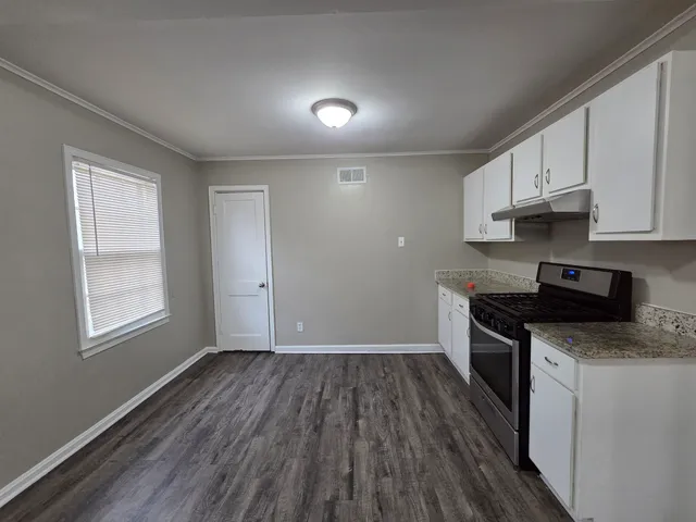 a kitchen with granite countertop wooden floors a stove and a microwave