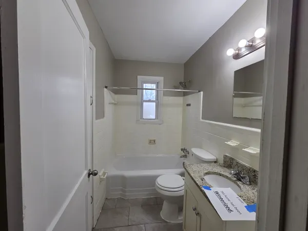 a bathroom with a granite countertop toilet a sink and a mirror
