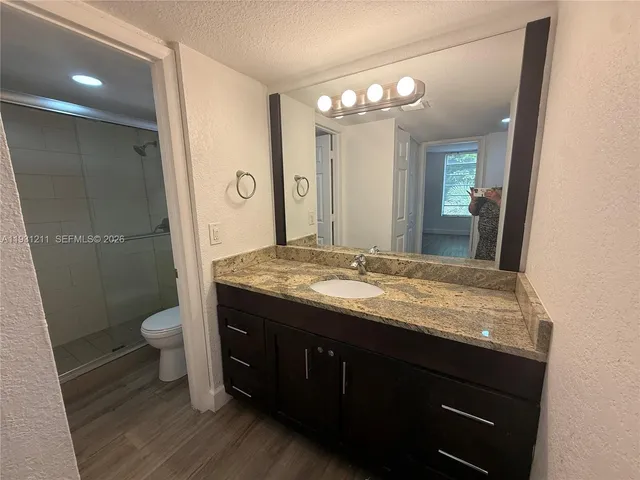 a bathroom with a granite countertop sink toilet a large mirror a vanity and shower