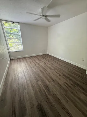 an empty room with wooden floor chandelier fan and windows