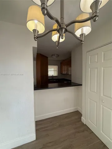 an empty room with a chandelier fan and wooden floor
