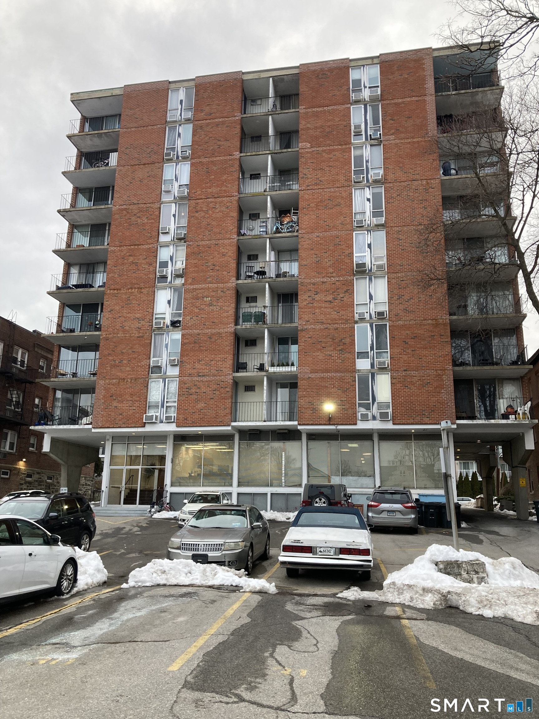 87 Glenbrook Road, Unit 6E Stamford, CT 06902 - Photo 20 of 23 a front view of a building with lot of cars and trees