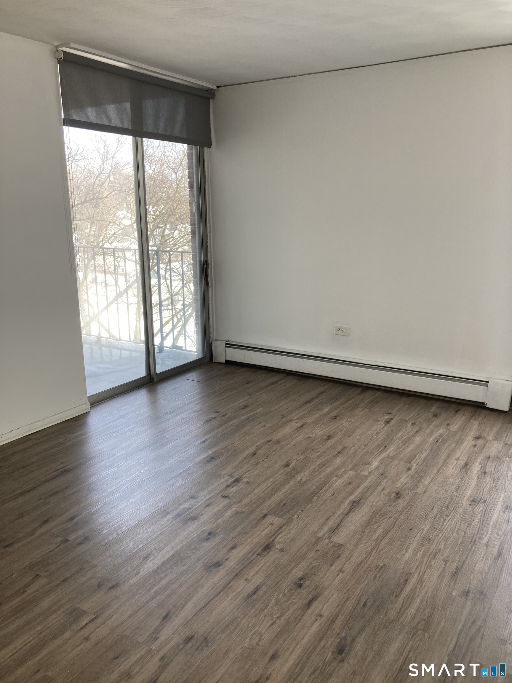 87 Glenbrook Road, Unit 6E Stamford, CT 06902 - Photo 9 of 23 a view of an empty room with wooden floor and a window