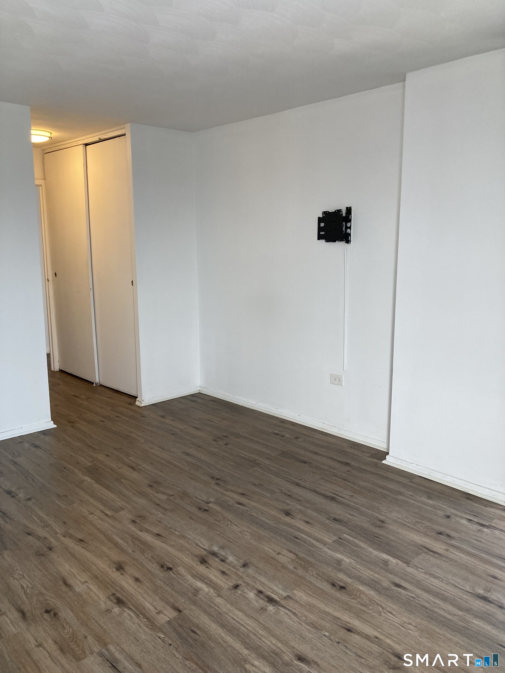 87 Glenbrook Road, Unit 6E Stamford, CT 06902 - Photo 10 of 23 a view of an empty room with wooden floor and a window
