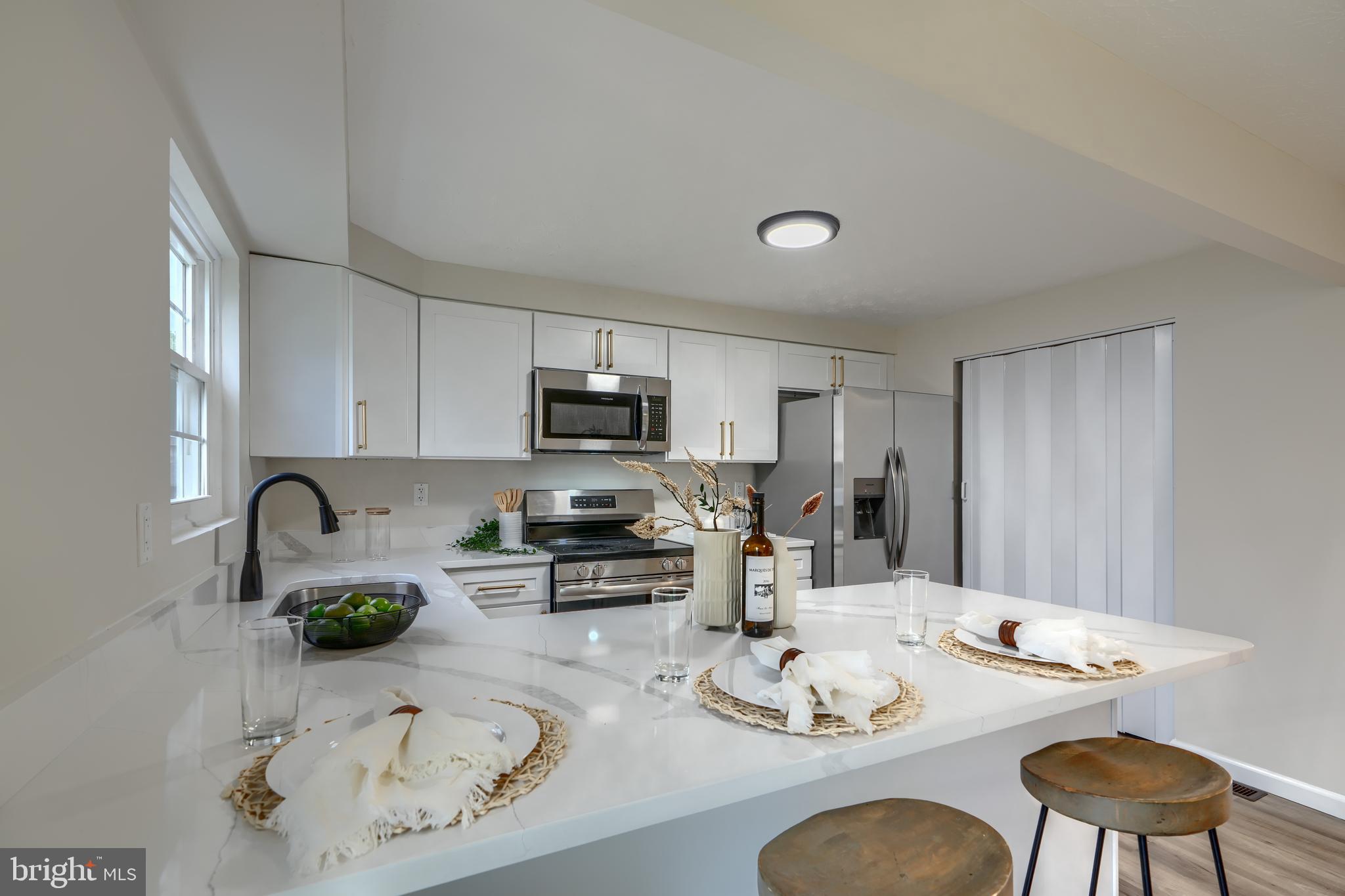 4008 Rustico Road Baltimore, MD 21220 - Photo 11 of 37 a kitchen with stainless steel appliances kitchen island granite countertop a sink a stove white cabinets with a dining table and chairs