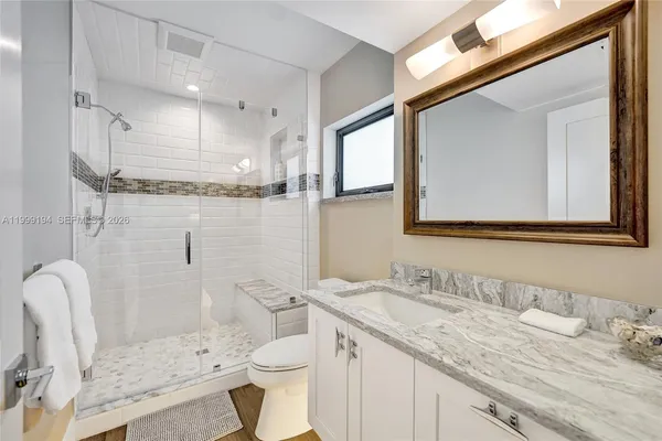 a bathroom with a granite countertop sink mirror vanity and toilet