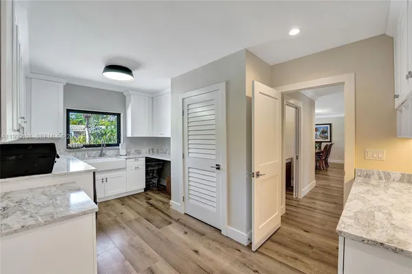 a large open kitchen with a refrigerator a stove top oven and a wooden floor