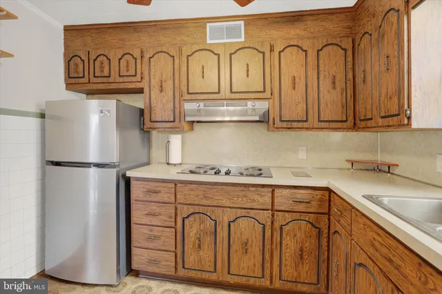 a kitchen with stainless steel appliances granite countertop a refrigerator a stove and a sink