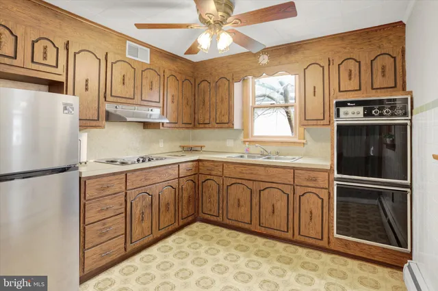a kitchen with stainless steel appliances granite countertop a refrigerator a sink and white cabinets