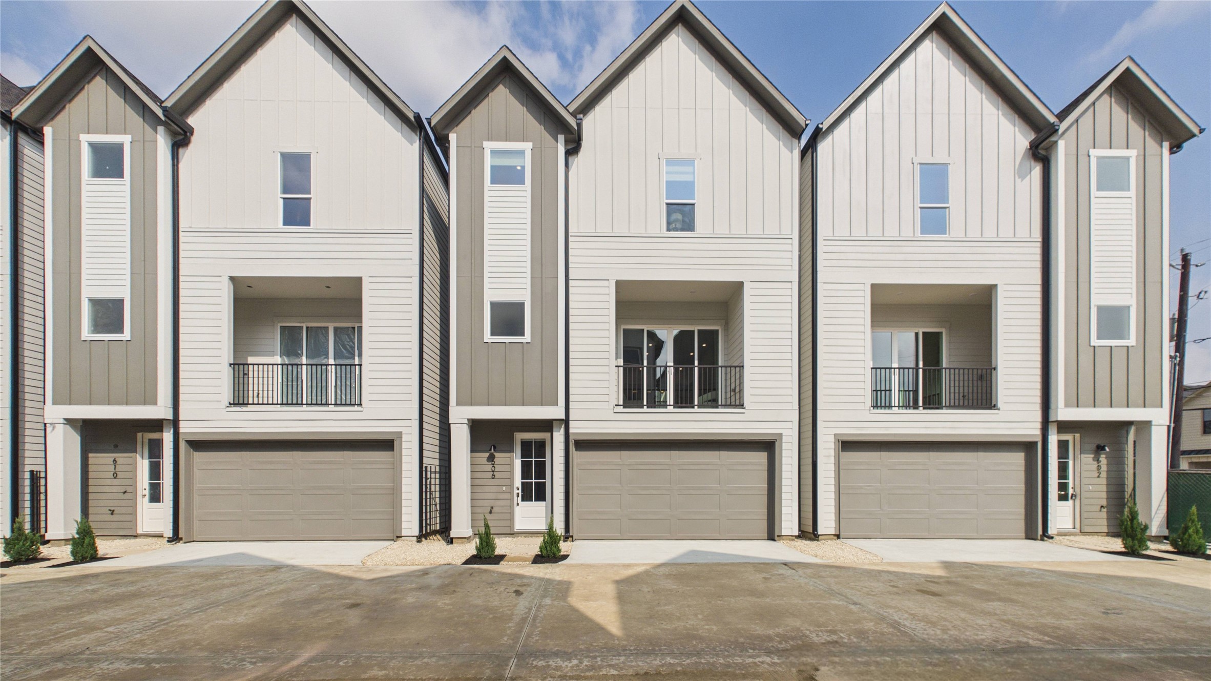 602 Skyland Terrace Way Houston, TX 77009 - Photo 2 of 40 Modern townhomes with a sleek exterior featuring vertical siding and neutral tones. Each unit includes a double garage, private balcony, and large windows for natural light. Ideal for contemporary living.