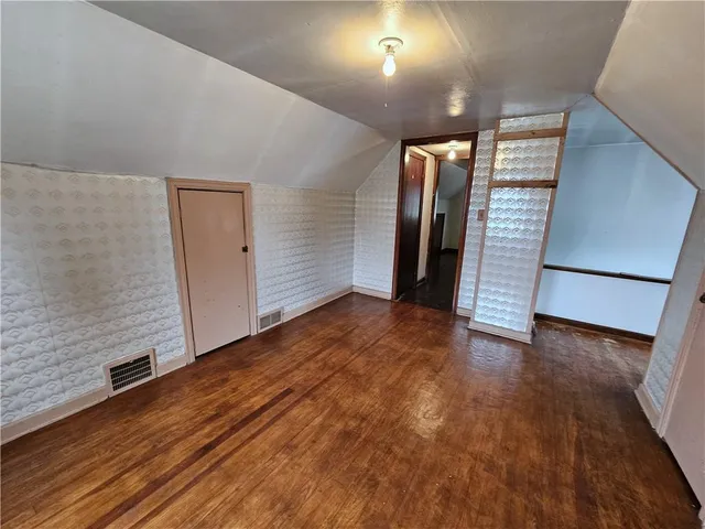 an empty room with wooden floor and entrance