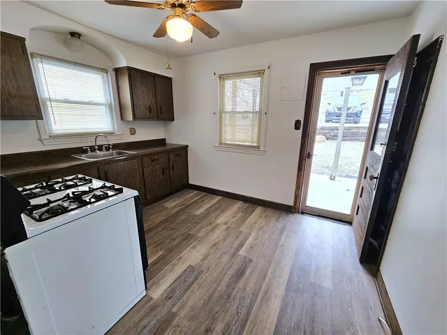 a kitchen with stainless steel appliances a stove a sink a refrigerator wooden floor and a window