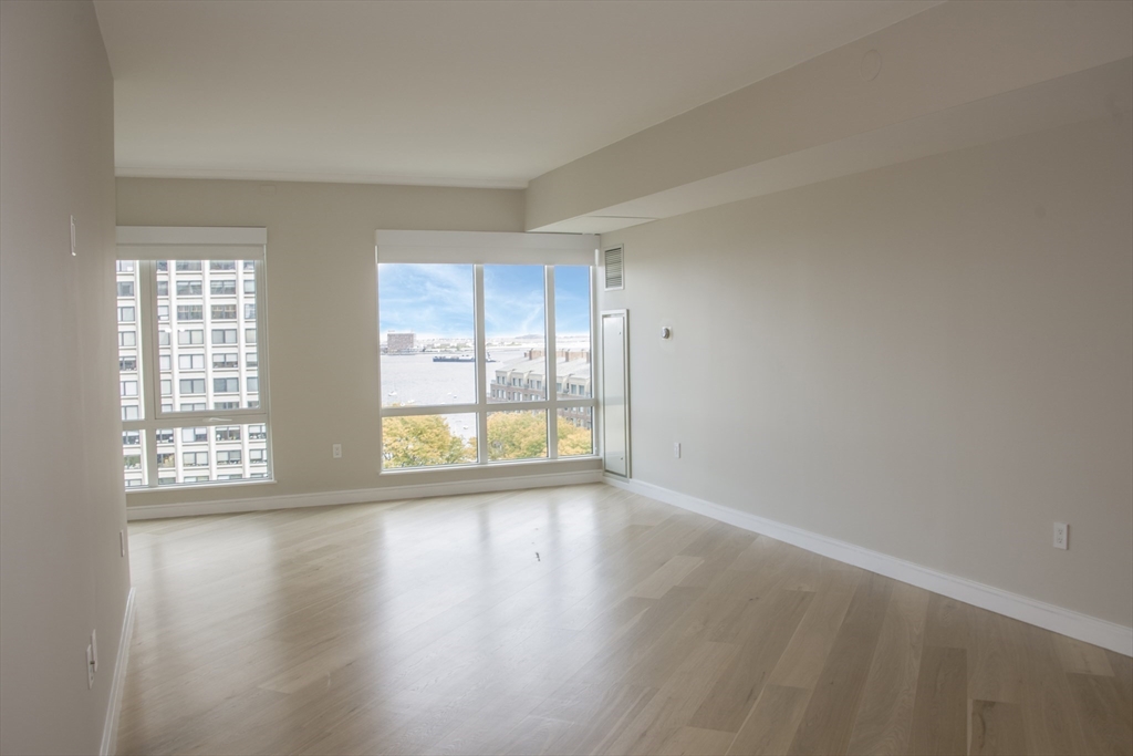 110 Broad Street, Unit 1102 Boston, MA 02110 - Photo 12 of 26 an empty room with wooden floor and windows