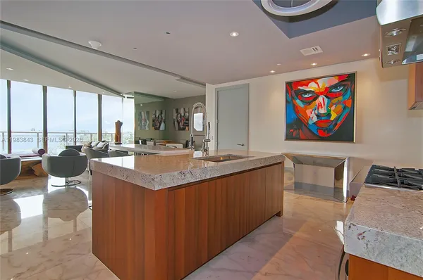 a living room with stainless steel appliances kitchen island granite countertop a sink and a refrigerator