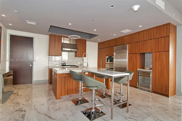 a view of a kitchen with kitchen island granite countertop a sink and a refrigerator