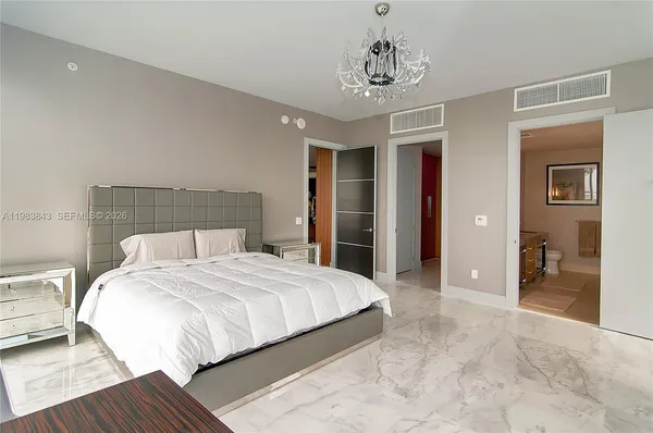 a bedroom with a large bed and a chandelier