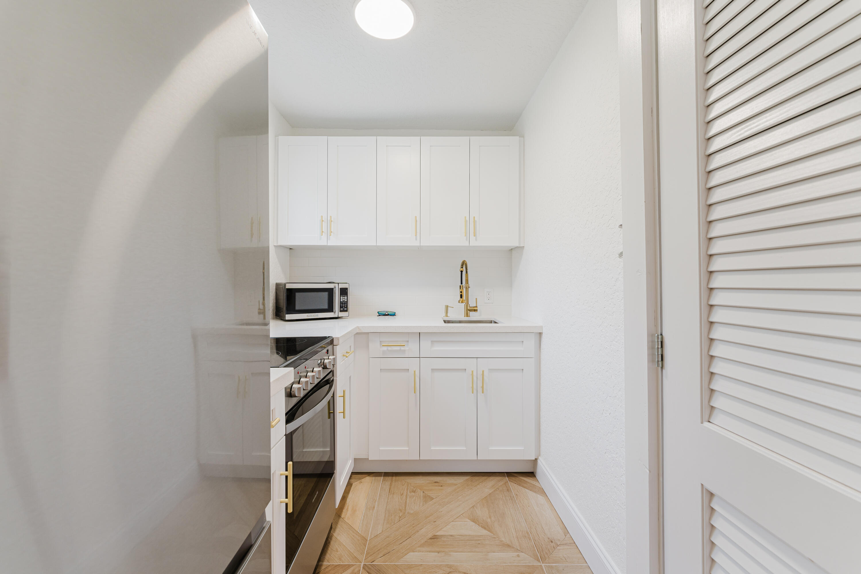 921 Ortega Road West Palm Beach, FL 33405 - Photo 38 of 60 a kitchen with white cabinets and white appliances