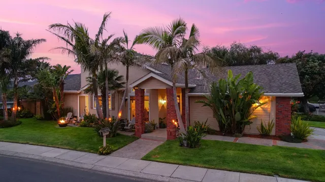 a front view of a house with a yard and potted plants