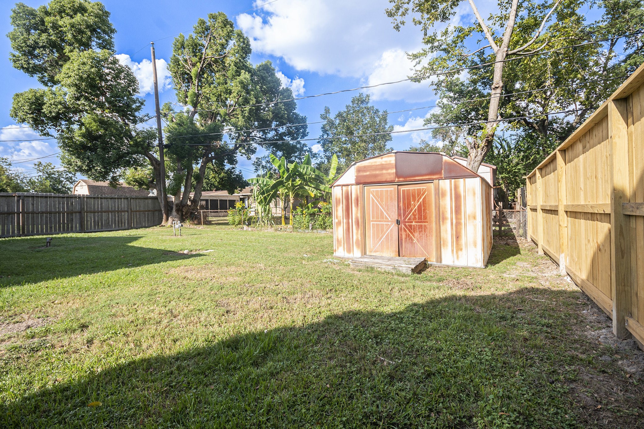 10619 Wheaton Drive Houston, TX 77089 - Photo 21 of 25 This spacious backyard offers a well-maintained lawn, mature trees, and a convenient storage shed, perfect for outdoor activities and relaxation.
