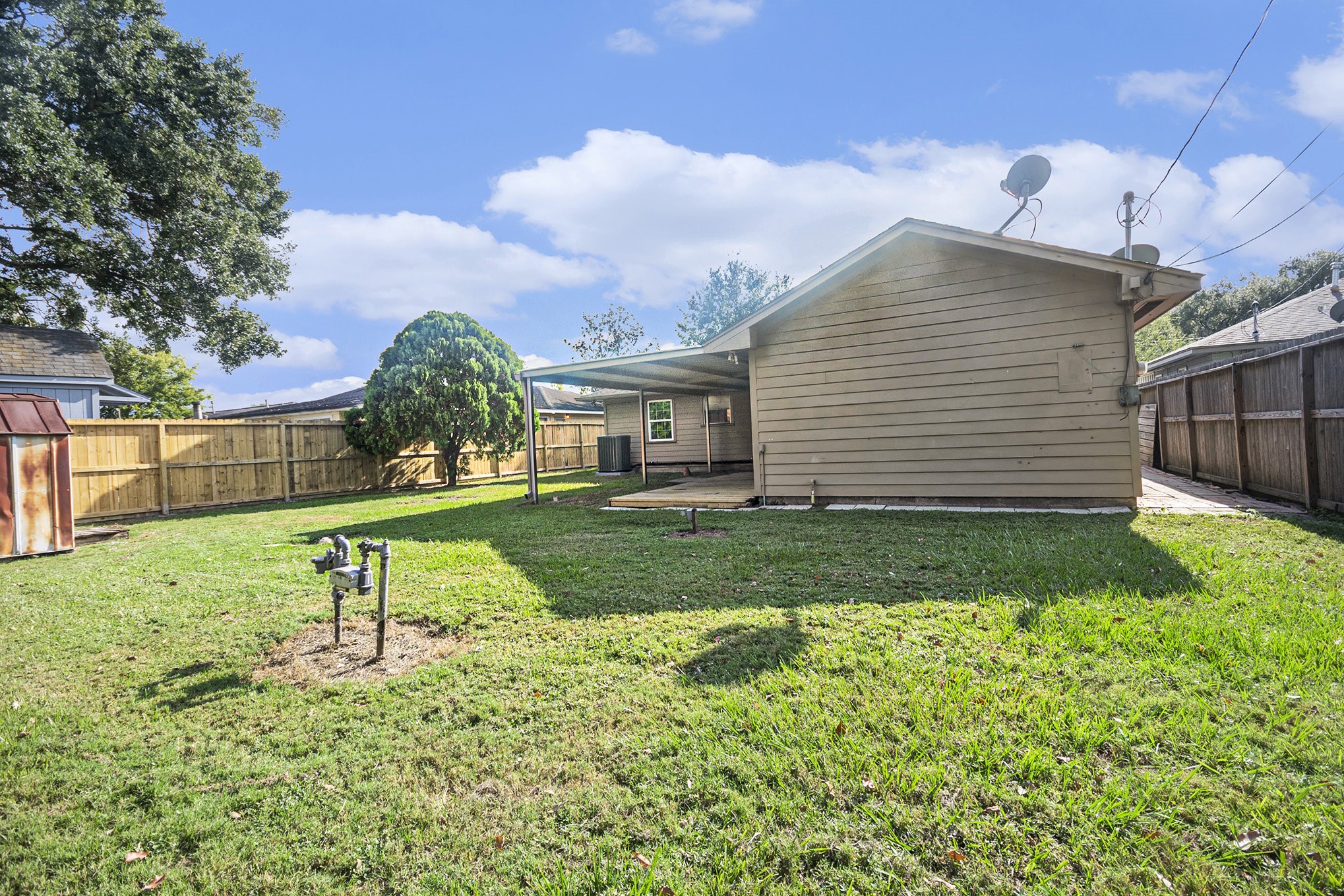 10619 Wheaton Drive Houston, TX 77089 - Photo 22 of 25 Spacious backyard with a covered patio, perfect for outdoor gatherings. Enjoy privacy with a fully fenced perimeter and additional storage space. Ideal for relaxation and entertaining.