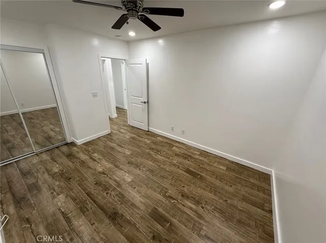 an empty room with wooden floor and a ceiling fan