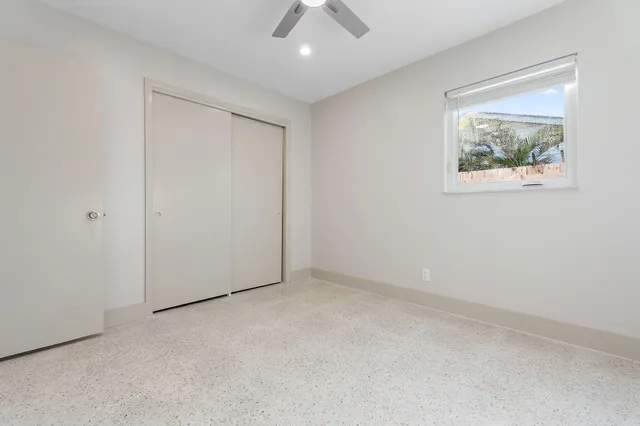 an empty room with a ceiling fan and a window