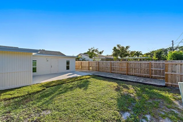 a view of a backyard with wooden fence and a large tree