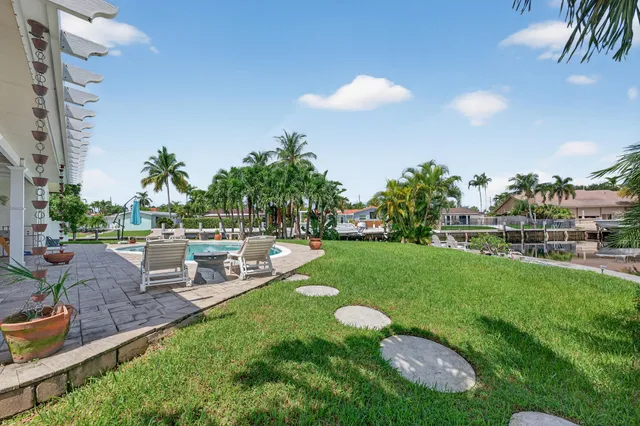 a view of a swimming pool with lawn chairs and potted plants