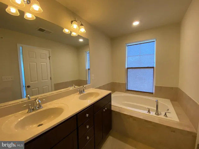 a bathroom with a double vanity sink a mirror and a bathtub
