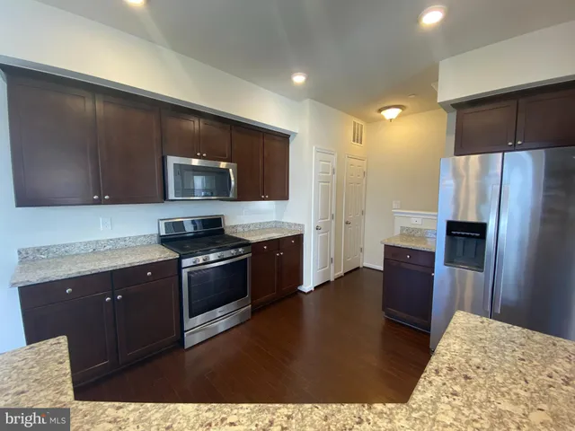 a kitchen with stainless steel appliances granite countertop a refrigerator stove and microwave