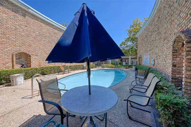 a view of patio with chairs and table under an umbrella