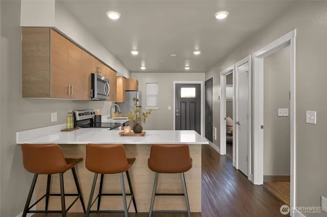 a large kitchen with stainless steel appliances granite countertop a stove a sink a refrigerator and a dining table with wooden cabinet