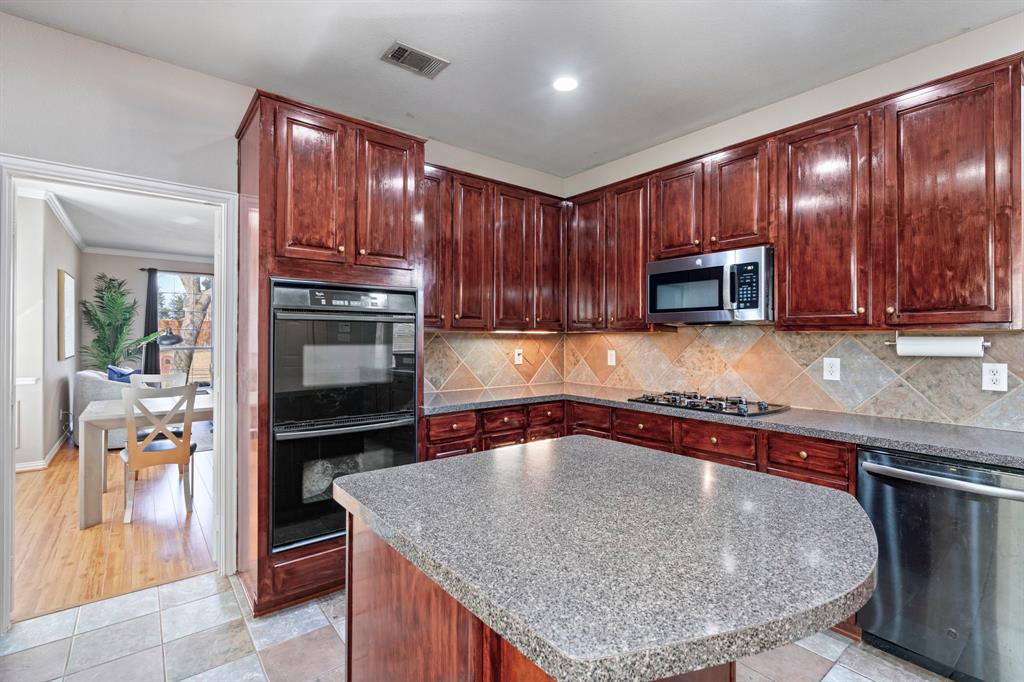 1105 Lamplight Way Allen, TX 75013 - Photo 19 of 40 a kitchen with kitchen island granite countertop wooden cabinets a stove and a sink