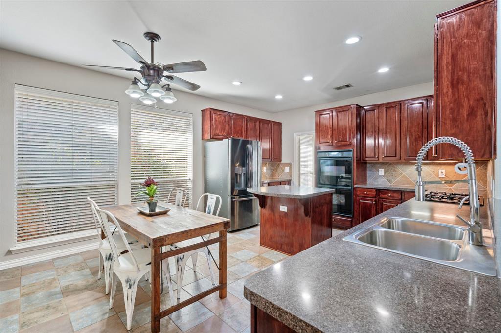 1105 Lamplight Way Allen, TX 75013 - Photo 20 of 40 a kitchen with stainless steel appliances granite countertop sink stove refrigerator dining table and chairs