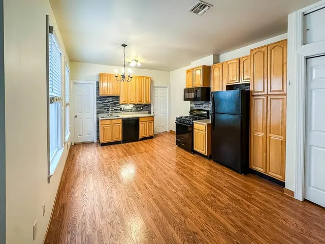 a kitchen with a refrigerator wooden floor a stove and a dining table