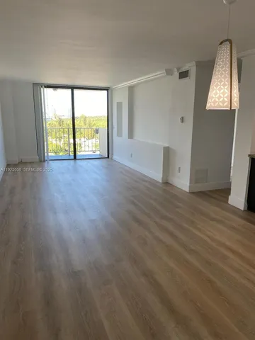 a view of an empty room with wooden floor and window